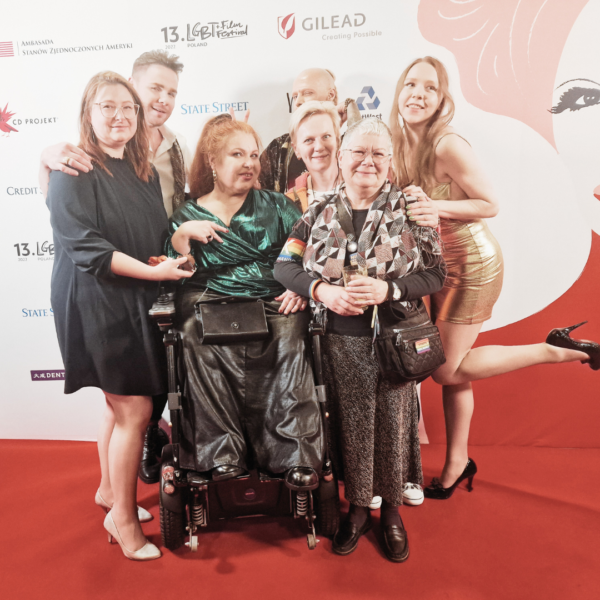 grupa ludzi w tym kobieta na elektrycznym wózku inwalidzkim, starsza kobieta o siwych krótkich włosach i jeden mężczyzna 